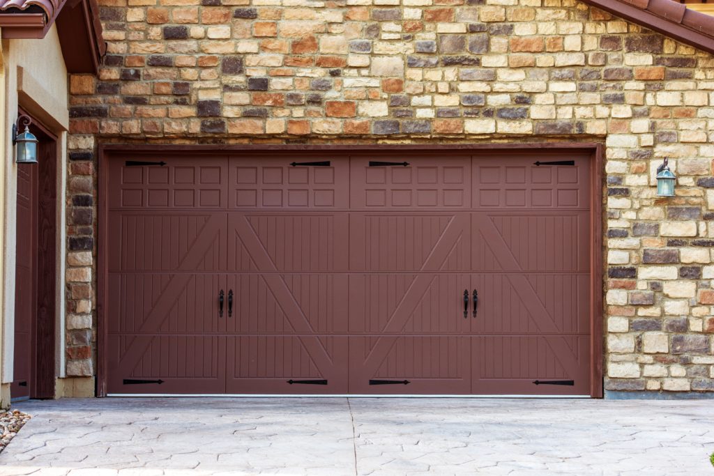 Wide brown garage door on stone house
