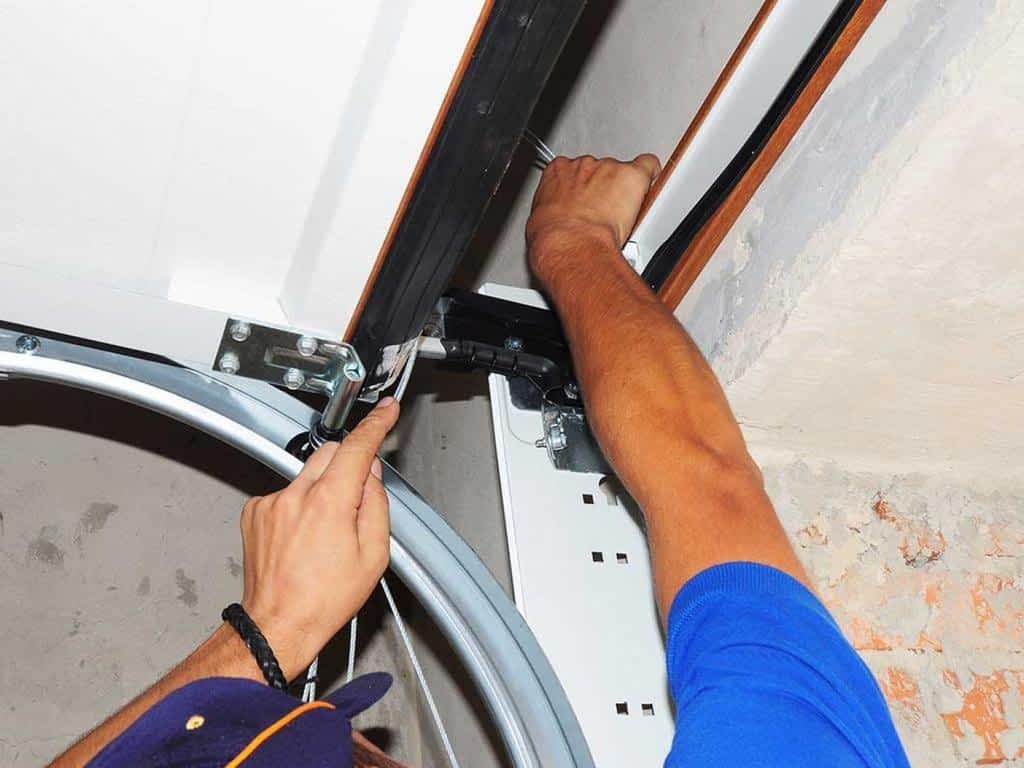 Employee fixing spring on garage door