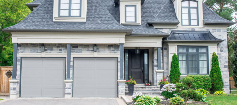 two door garage with long grey recessed panel doors on a modern home